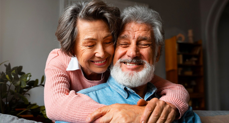 Una pareja de adultos mayores abrazada sonriendo