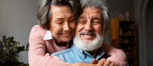 Una pareja de adultos mayores abrazándose y sonriendo.