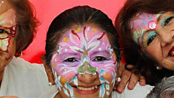 Fotografía de tres mujeres de la tercera edad con maquillaje de carnaval sonriendo.