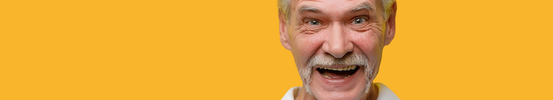 Fotografía primer plano del rostro de un señor de la tercera edad muy sonriente, sobre un fondo de color amarillo.