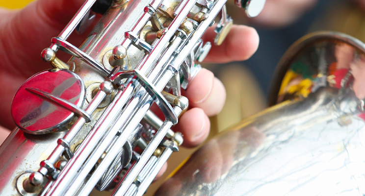 Fotografía de detalle de una mano manipulando un saxofón