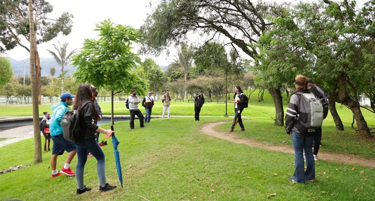Fotografía de un grupo de caminantes en un parque distrital guiados un una colaboradora del IDRD