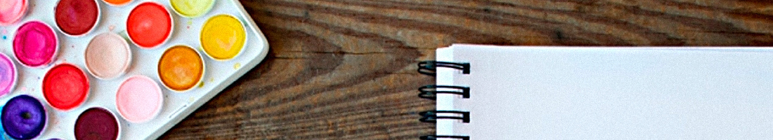 Fotografía en primer plano de una paleta de acuarelas y una libreta de bocetos en blanco
