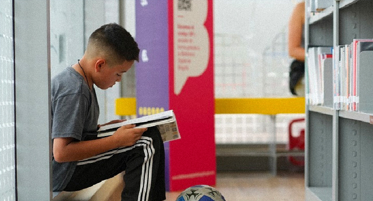 Foto de un niño leyendo en la biblioteca