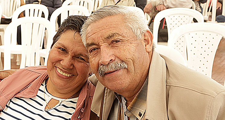 Fotografía de dos personas de la tercera edad, hombre y mujer compartiendo juntos y sonriendo