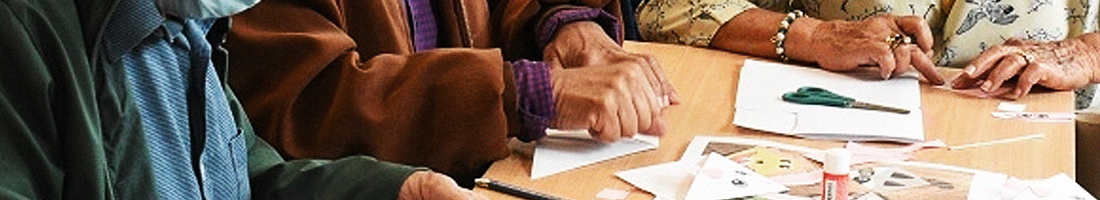 Foto en primer plano de varias manos de adultos y adultas mayores trabajando con sus manos sobre una mesa de taller.