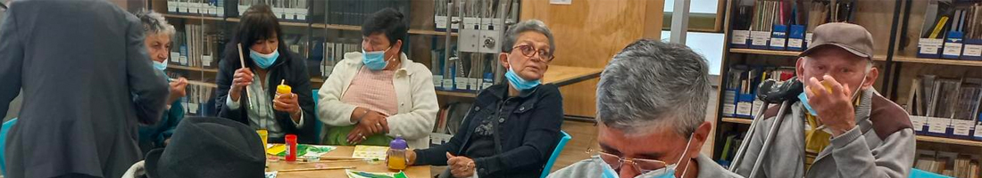 Fotografía donde se aprecian adultos mayores en espacio de taller realizando manualidades