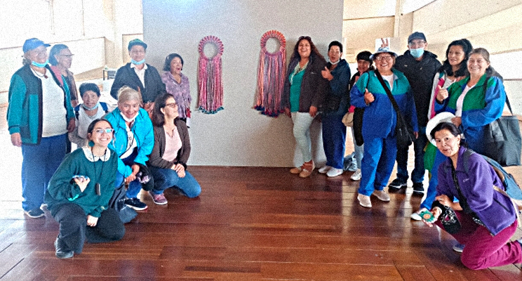 Fotografía de señoras de la tercera edad posando para la foto acompañadas de una escultura