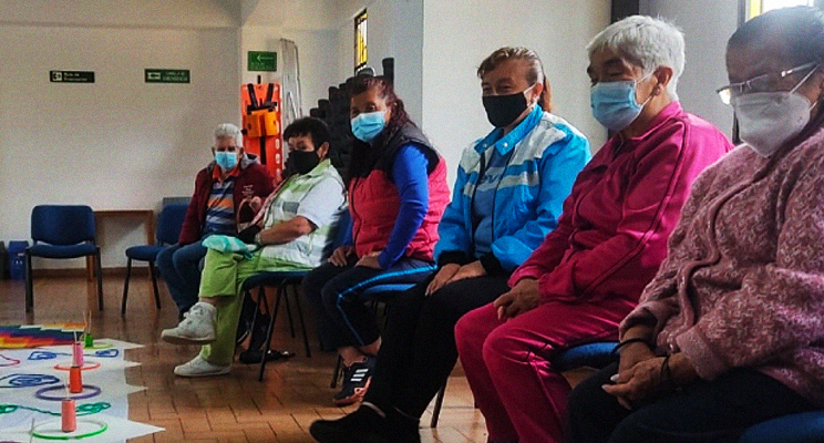 En la foto se pueden apreciar mujeres adultas mayores sentadas en el espacio de taller de la biblioteca
