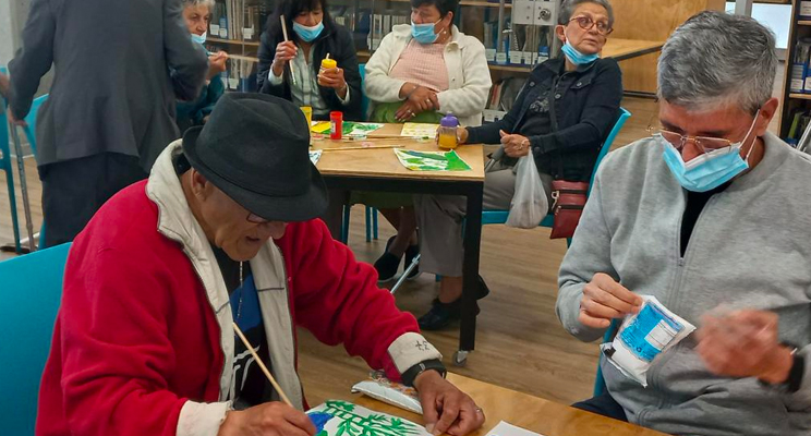 Fotografía donde se aprecian adultos mayores en espacio de taller realizando manualidades