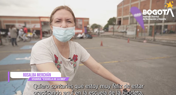 Fotograma del video promocional donde sale la Señora Rosalba Merchán (ciudadana) usuaria del programa "Escuela de la bici", en texto de close caption dice: "Quiero contarles que estoy muy feliz de estar practicando aquí en la escuela de la bicicleta"