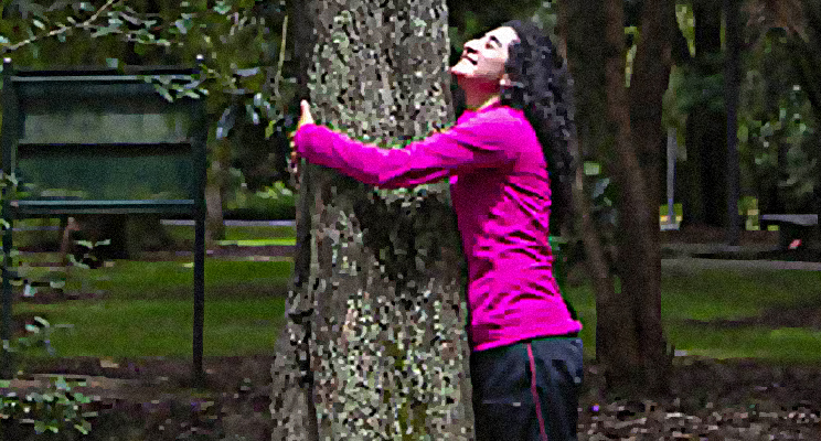 Fotografía de una mujer de cabello crespo negro abrazando un árbol en el Jardín Botánico de Bogotá
