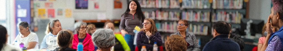 Grupo de adultas mayores en la biblioteca debatiendo.