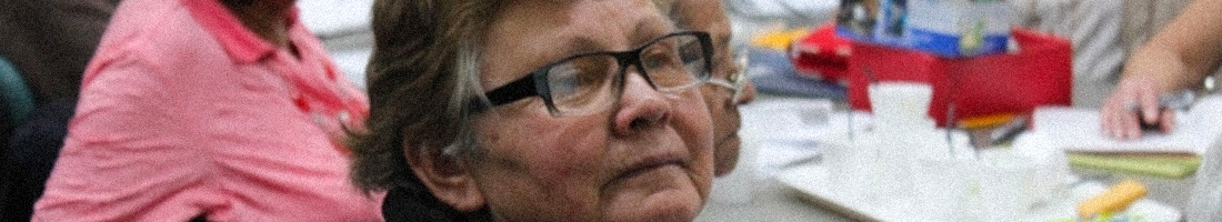 Señora de la tercera edad con gafas prestando atención en el espacio de taller