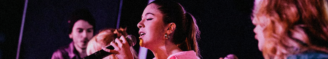 En la foto tres jóvenes cantando