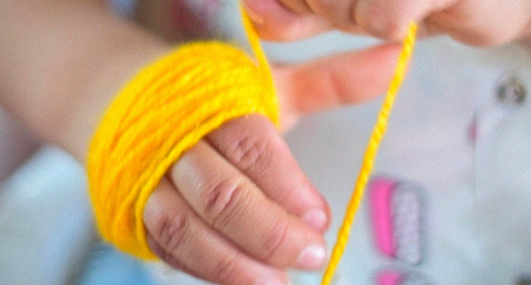 Mano pequeña con lana amarilla