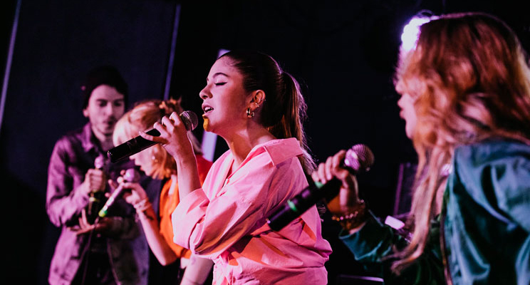 En la foto tres jóvenes cantando