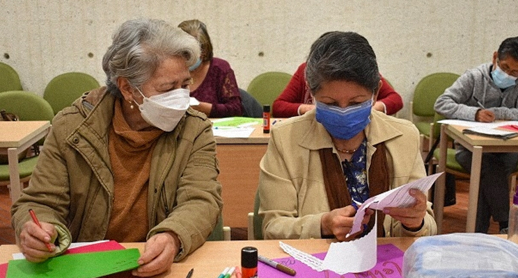 Señoras de la tercera edad realizando actividades en espacio de taller en la biblioteca