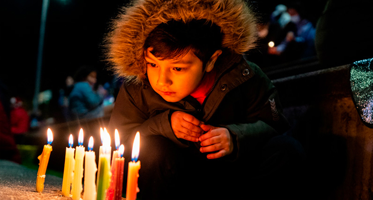 Foto de velitas encendidas y de fondo las manos de un niño