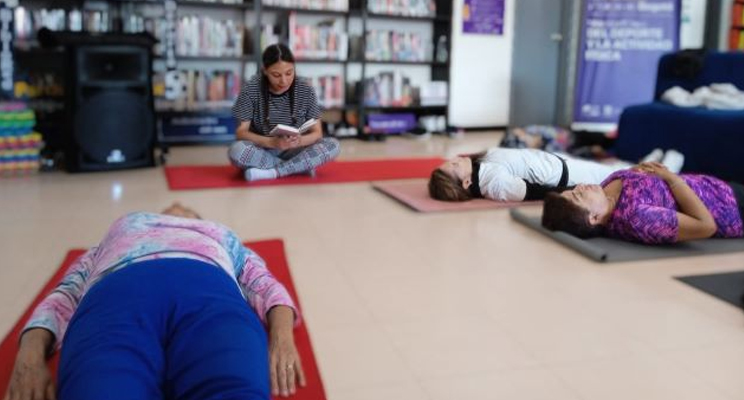 Mujeres en la biblioteca haciendo yoga.