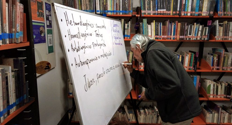 Señora de la tercera edad participando activa en el taller escribiendo sobre el tablero