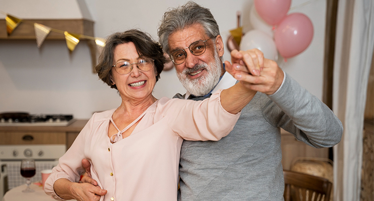 Pareja de personas mayores bailando y sonriendo