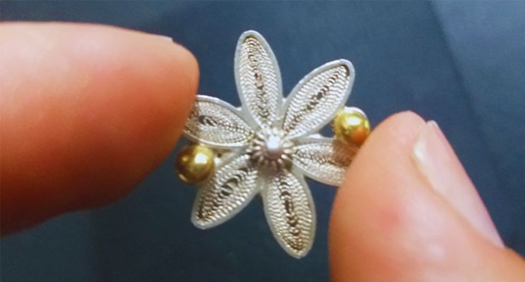 imagen de mano sosteniendo flor hecha en filigrana