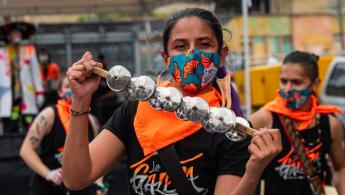 Mujer interpretando instrumento de metales en la calle acompañada de la comparsa que la sigue