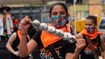 Mujer interpretando instrumento de metales en la calle acompañada de la comparsa que la sigue