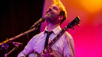 Kevin Johansen con la cabeza en alto sonriendo e interpretando el banyo.