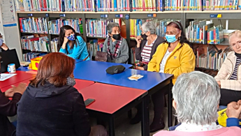 Fotografía de un grupo de señoras de la tercera edad compartiendo un diálogo en la biblioteca.
