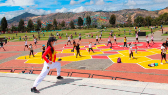 Fotografía de varias personas realizando entrenamiento colectivo en una recreovía de Bogotá, guiada por una colaboradora del IDRD.