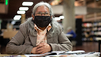 Fotografía de una señora de la tercera edad en la biblioteca.