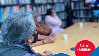 Fotografía de personas de la tercera edad en un espacio de proyección audiovisual de una biblioteca.
