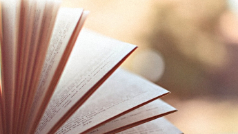 Foto en primer plano de un libro abierto y sus hojas cayendo