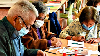 Personas de la tercera edad concentradas en un espacio de taller en la biblioteca.