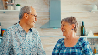 Foto de dos personas de la tercera edad, hombre y mujer viéndose a la cara y sonriendo.