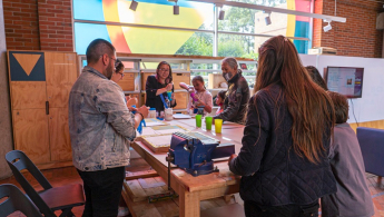 Fotografía de un grupo de adultas y adultos mayores en la biblioteca en un espacio de taller