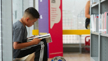 Foto de un niño leyendo en la biblioteca