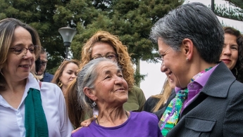 Foto donde aparece la Alcaldesa Claudia López acompañada de una señora de la tercera edad sonriendo y a su lado otra directiva distrital.