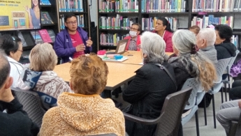 Grupo de adultas mayores compartiendo lectura en la biblioteca
