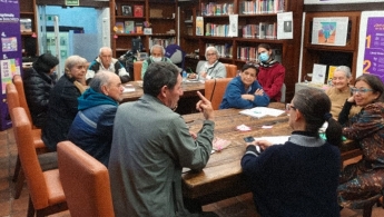Personas mayores debatiendo en espacio de taller en la biblioteca.