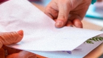 manos de adultos mayores intercambiando cartas en el espacio de taller