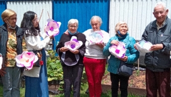 Personas de la tercera edad posando para la foto mostrando sus cartas.