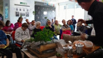  Señoras de la tercera edad en el espacio de taller, atentas al expositor que trata con una planta