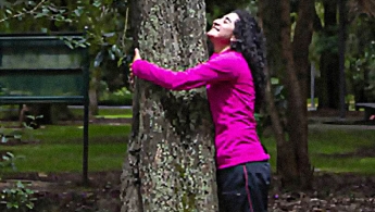 Mujer abrazando un arbol de manera terapéutica