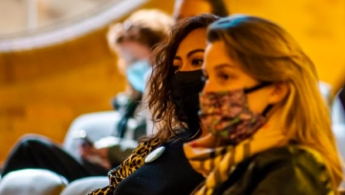Mujeres con tapabocas en un auditorio dirigiendo su mirada hacia la izquierda