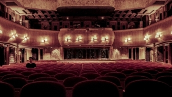 En la foto se ve un teatro vacio con solo una persona en el público