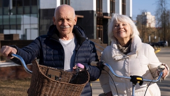 Dos personas mayores sonriendo y sosteniendo sus bicicletas