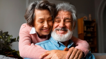 Una pareja de adultos mayores abrazada sonriendo